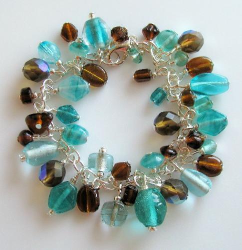 Waterfall Bracelet - This 7 1/2' silver plated charm-style bracelet is adorned with an assortment of glass beads in aqua blues and browns. There are 5 czech fire polished faceted beads in light brown, that pick up the aqua blues well. A great color combo for fall! Avaailable in my Etsy.com shop.