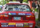 so many labels  - red car with bumper stickers all over back