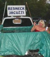 Redneck Jaquzzi - A white trash woman sitting in a back of a truck that has a tarp in bed of truck holding water in.