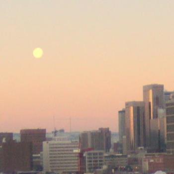 moon over the city at dawn - first light of day and the moon still hangs over the city