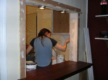 Putting finishing touches on the pass-thru we buil - This was near the end of what we dubbed "phase 2" of the kitchen remodel. We cut a pass thru between the living room and the kitchen and added a little counter to sit at.
(Phase 1 was when we removed the unused chimeny from the kitchen and drywalled. The end result was just a flat wall, so not as cool of an "after" shot)