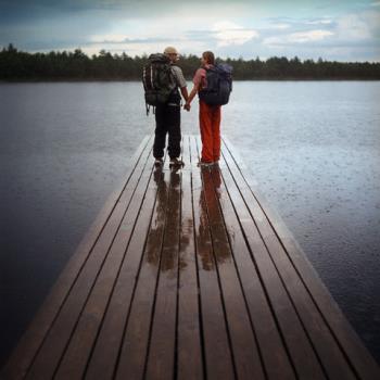 relationship - 2 backpackers standing on the dock in the middle of the rain