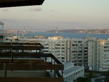 View of Lisbon, Portugal and Surrounding Area - photo I took from my balcony showing the Tagus River Statuary, the 25th of April bridge (formerly the Salazar Bridge) and the Statue of Cristo Rei (Christ the King Statue), an a small portion of the Port of Lisbon. The bridge was built by the same company as that which built the Golden Gate in San Francisco, but it is not an exact replica. The Cristo Rei is similar to the statue of Christ the Redeemer in Rio de Janeiro atop the Corcovado mountain. 