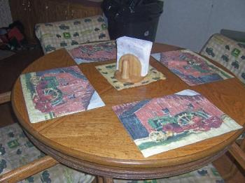My Kitchen Table - This is a photo of my kitchen table...it has the John Deere place-mats, John Deere fabric covering the cushions of the chairs, and a John Deere bandana which holds the wooden napkin holder/salt & pepper.....on top of a wooden table and the chairs have wooden arms & legs...