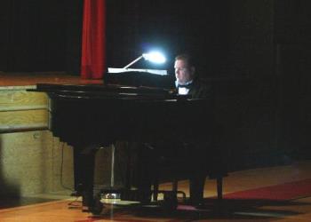 Piano Soloist - This photo was taken from across the auditorium. I had to adjust the settings for the light comming from the stage and the very bright light of the panio light. Being an indoor concert I could not use a flash. I had only a couple of chances to take the photo. I was using a tripod and the canon rebel with a 50mm f1.8 lens. I set the camera at an ISO of 1600 and focused on his face.