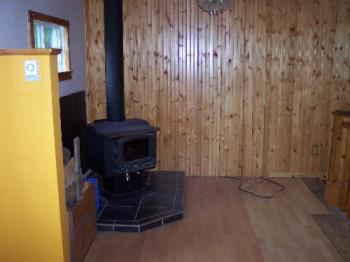My woodstove, with wood panelling behind it. - Here you can see my woodstove in my new house, it is currently not far enough from the wall and the pipe is upside down, but we are going to fic it before we run it.