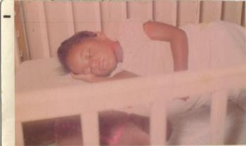 Me As A Kid -  This is a picture of me. I was asleep in my baby bed. Though God knows, I was much too big to be in it.