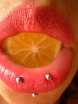 Lip piercings - Woman with lip piercings and lemon