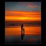 Mother - a mother taking care of a child. they both watch the sunset go down by the beach.