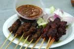 satay - marinated meat bbq&#039;d on skewers served with cucumbers and rice cakes topped with groundnut sauce.