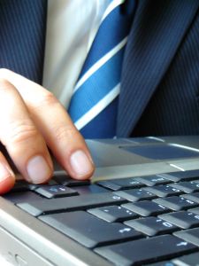 Businessman at computer - A picture of a businessman in a suit and tie sitting at a laptop computer. His body language suggests that he is frustrated.  A royalty-free stock photo from StockXchange, www.sxc.hu