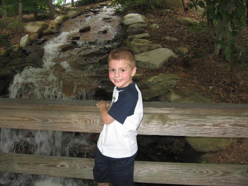Bryson at the waterfall - Bryson is standing by the waterfall at Six Flags, posing for his picture. He had so much fun that day.