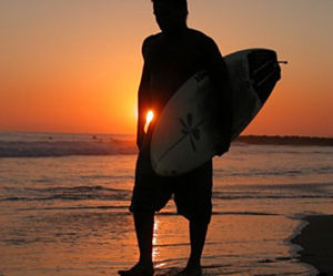 Surfing - Surfing is a surface water sport in which the participant is carried by a breaking wave on a surfboard. There are various kinds of surfing, based on the different methods or surf craft used to ride a wave. The basic categories include regular stand-up surfing, kneeboarding, bodyboarding, surf-skiing and bodysurfing. Further sub-divisions reflect differences in surfboard design, such as long-boards and short-boards. Tow-in surfing involves motorized craft to tow the surfer onto the wave. It is associated with surfing huge waves, which are extremely difficult to ride and sometimes impossible to catch by paddling down the face, due to their rapid forward motion.