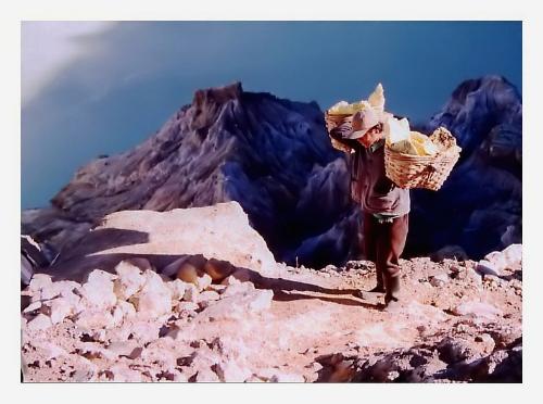Kawah Ijen Minner - I tried to improve the scan quality but that&#039;s the best I could do, my poor old scanner is not coping with the tasks too well anymore, or I can&#039;t cope with PP well enough...
So here&#039;s one of the miners from Kawah Ijen. They climb up the crater and then down to its acid lake 2-3 times a day, each time carrying back a weight of 70-80 kg of sulfur. And they earn several dollars a day...I saw a tall, muscular Italian guy try to lift the basket, he could hardly do this for several seconds, while the climbers have to cover about 3 km to the weighing point, including a steep and dangerous climb into and out of the crater. I only took a look down the path, and gave up...good thing my travel companion had more courage and got there to take some photos. 
It was only 10 a.m. and the sun was already very strong, my eyes hurt, but after all, we were actually over the clouds. The blue area in the background is the acid lake I was writing about.
I was fascinated with the view of the crater and its torquise lake, but seeing the miners I thanked God I&#039;ve been spared a life like theirs...