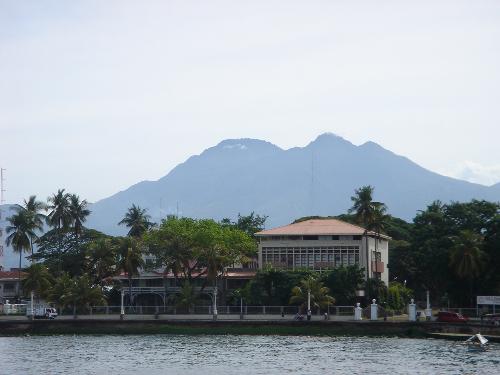mount kanlaon - on the background is mount kanlaon looming behind silliman university's business school building (which is one of the university's numerous buildings). on the foreground is the pier's waters..