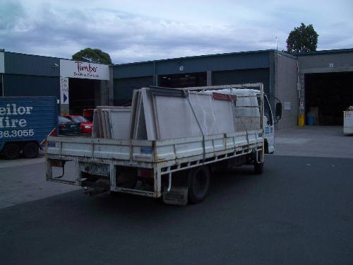 Granite and marble bench tops on an A-frame on a s - Granite and marble bench tops get delivered to a yard by a small 3 tonne truck. An Isuzu 200, 110 SiTec in fact. Melbourne, Victoria, Australia.