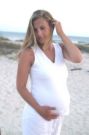 pregnant - mom to be in a white outfit at the beach