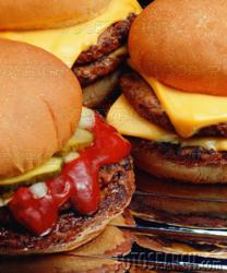 cheesebuger - a picture of several cheeseburgers fully cooked with cheese. Some of the are plain others have ketchup and pickles. They are on hambuger buns.