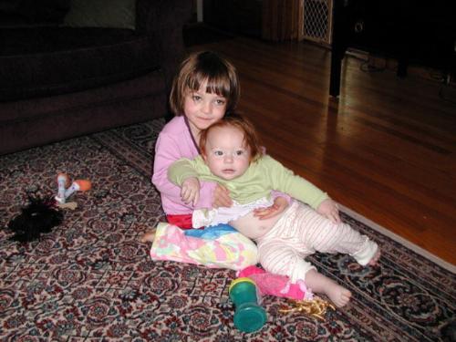 Sisters - They are sisters. The elder one is supporting the younger sister in her lap.