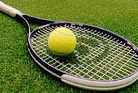 tennis - This is a photo of a tennis racquet and tennis ball on grass.