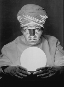 Futurists - The man is scrying to help him percieve his psychic abilities . the crystal ball helps him see the past,present and future. The looks of him arouse a question of his authenticity.