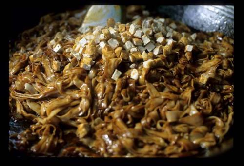 fried noodles - On the way to cook,char kway teow cooks with black soy sauce and bits of tofu on top.