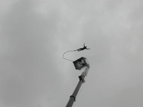 Bungee jumping - Picture of a person jumping off an elevated platform with the bungee cord tied to his legs.
