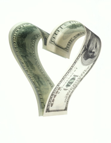 Love of money - Image of two 100 dollar bills curled into a heart.