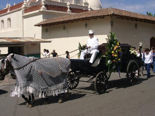 Funeral procession In Masaya Nicaragua - This is a picture of a funeral procession in Masaya, Nicaragua. If the person has enough money to hire the wagon and driver they do, or they use the back of a pick-up truck sometimes. If they can't afford that pall bearers carry the casket sometimes for very long distances. The photo is one of the more typical funerals.