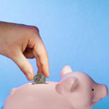 save money - photo of someone putting money in a piggy bank