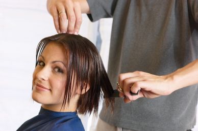 What do you do during a haircut? - A picture of a lady having her hair cut.
