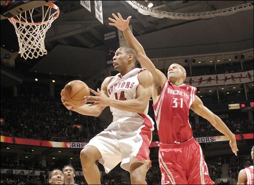 Joey Graham penetrates the defense - Joey Graham going for an easy basket after passing by Shane Battier of the Rockets while Chris Bosh cheers on.