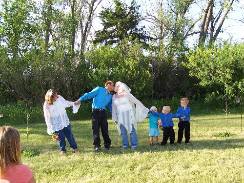 My wedding - My wedding photo of the kids re-enacting the tradition of trying to 'pull us apart'. Backyard wedding, beautiful day with trees as the background. Beautiful green lawn with wedding party and little kids in the foreground.
