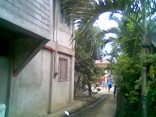 our house (in the middle of the street) - actually its not in the middle of the streets. ^__^;; seen here on the left side is the wall of our house and zooming in you can see some people up front playing basketball. there's a half court in front of our house and my uncle sometimes host games and gives trophies to winners. extending 25 meters more up front is a lake which is laguna lake, the largest lake in our ountry. 20 meters from the back of our house is a small mountain which i used to climb up when i was still a kid. ^__^