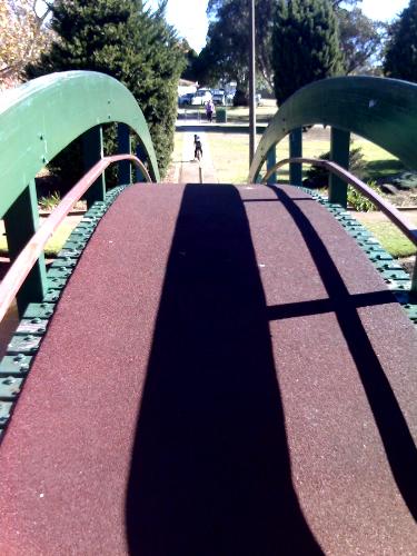 Bridge - Photo taken almost a year or so ago, by a friend of this I think, using phone. Also a bridge on which many feets and walks of life have stepped on, in this short little town place. The perspective view of this allows a viewers eyes to be lead to the midsection and to the end of the bridge. the marroon bits of this bridge cover the green-painted wood blocks. They are fleshy and foamy and such a surface may have tennis played on it. blaaaaaar darrr daaaah.