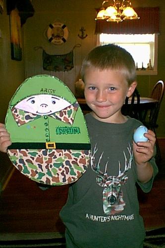 My son and his Army Easter Egg. - This is a picture of my son with the Easter egg he made for school. He is also wearing one of his shirts that has the camo on it. The other side of the egg says USA on it and is decorated in Red, White, and Blue.