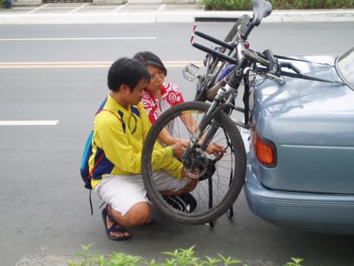 bike rack - a biker trying to lash his bike on the rack of his car