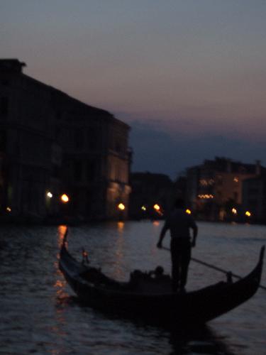 Gondola Night - Another sweet picture of a Gondola in Venice (taken May 2006). The lighting wasn't that great from the boat we were on, but it ended up painting a great picture. It looks more like a painting than a photography, but hey I like the way it looks. It also makes a cool outline of the Gondola, and its Gondoleer, Mario (just kidding I have no idea what his name is, but good guess right?). I only know a little bit of Italian, Spaghetti! Luigi! Pizza!