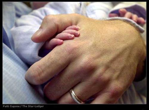 hand in hand - holding an infant's hand.