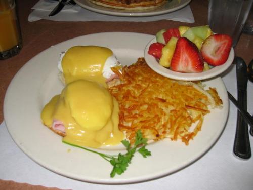 eggs benedict - Eggs benedict, hash browns, and fruit.