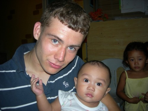 James and Baby Filipino girl - This is my son and one of the little ones in a church in Manila. He is with 4 other young men on a mission trip to the Philippines.