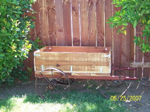 My flower cart my husband made me - The flower cart was made by my husband the wheels are antique wheels from an old cart which held tanks for wielding. He build the box and added the handles.