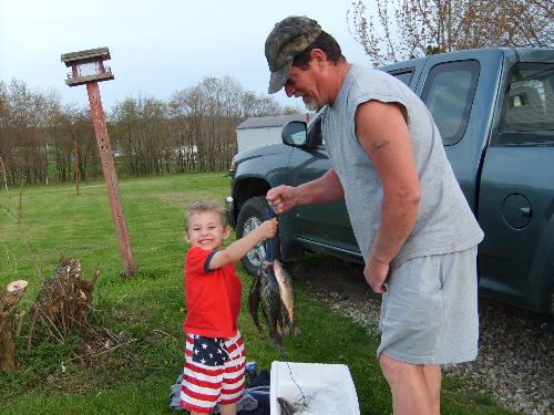 Hunter's first fish - THis picture was taken about a month ago. That is my son with my dad. And that is his first fish.lol How cute.