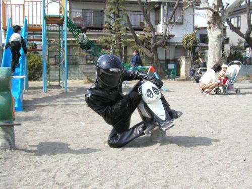 Too big - A motorcycle man plays on child equipment in a play ground
