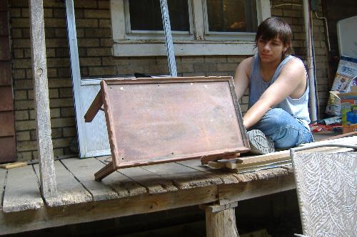 The table sanded - My teenager is holding my table that is newly sanded. This is before painting. The flat part here is what is now flat black and it has 4 rosebuds on it now.