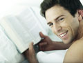 Good Looking guy - good looking guy laying in bed reading a book with a cute smile