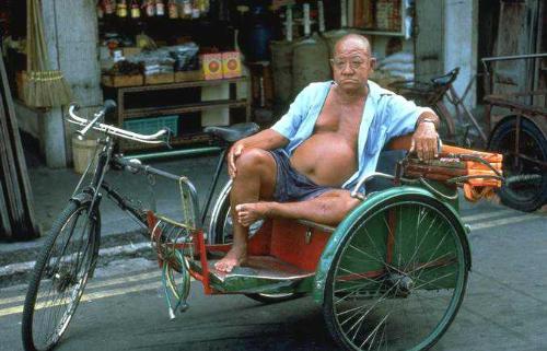people, - a man form Asia resting on is carriage,