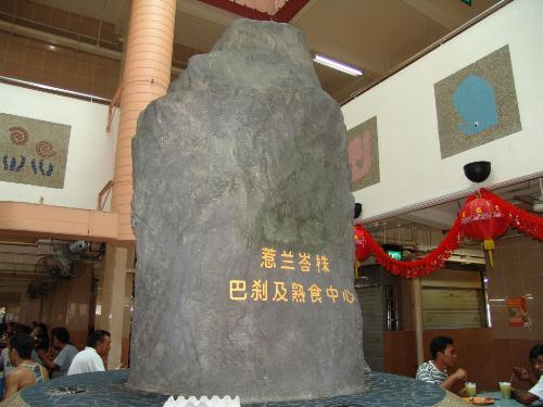 Rock At Jalan Batu Market Singapore - This is the strange rock in Jalan Batu Market, Singapore (Batu means rock in Bahasa Melayu). There are some mystery and history behind this rock:  1) It used to have an original inscription but was covered by cement.  2) The rock was said to stand in a 'blood-bathed' slaughter market and the shape of the stone resembled a tomb stone. When viewed from above, the rock seems to be in a concept of being submerged in water.  3) This rock was said to be sacred and people gave offerings of joss sticks to the rock.  4) On the upper levels of the market itself, shops near the rock seemingly resembled a typical chinese funeral parlour.