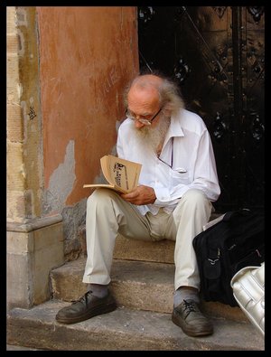 People - A old guy reading a book on the steps of his front door.