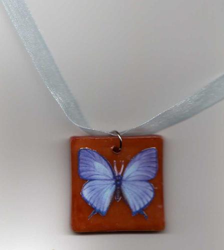 Blue Butterfly Pendant - Made of polymer clay, stained in a rich terracotta color and decoupaged with a Butterfly print. Pendant is coated with a gloss finish glaze and comes on a sheer ribbon necklace.